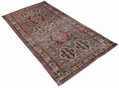 A rectangular vintage Persian rug featuring a dark grey field with intricate red and brown patterns.