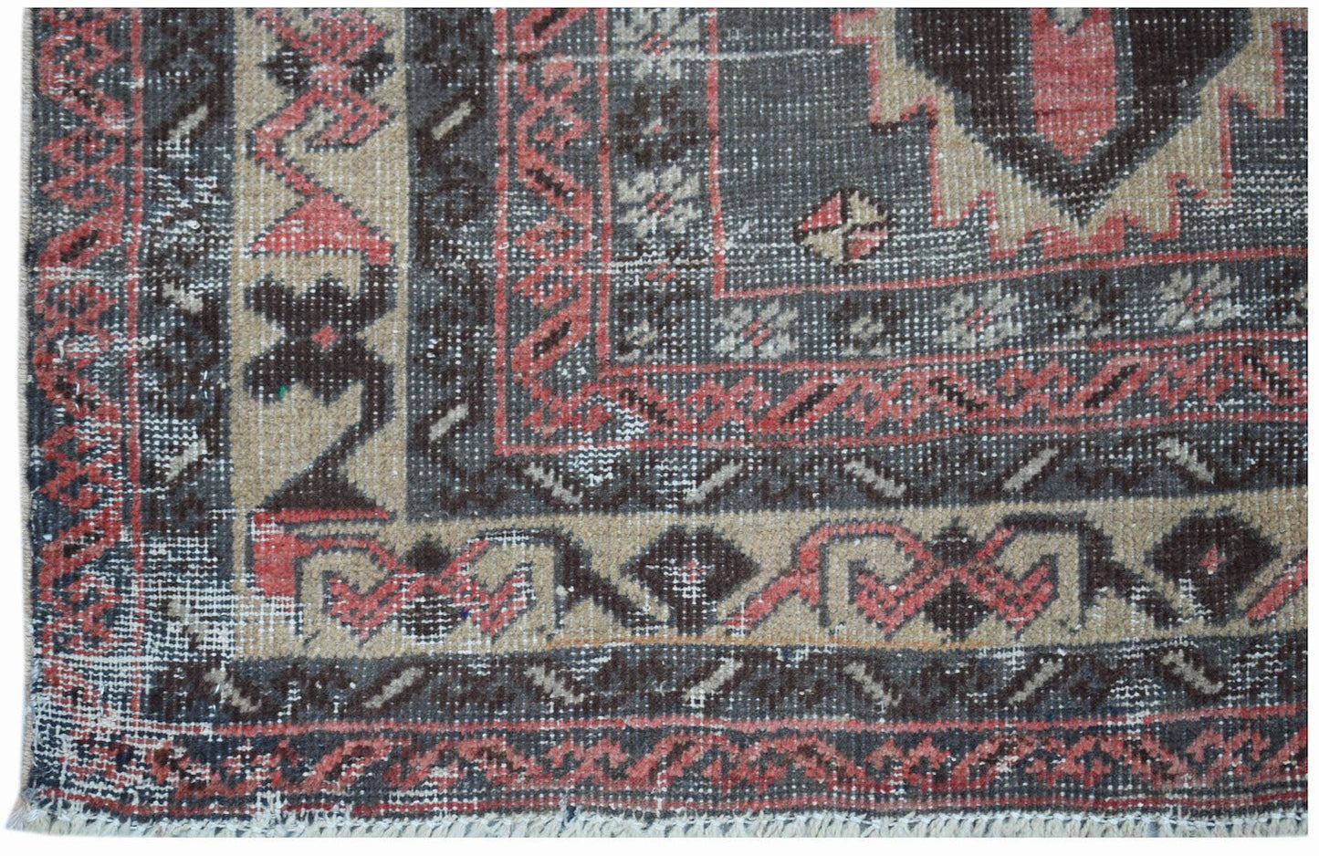A vintage handwoven Persian rug featuring a geometric pattern in shades of red, black, and beige.