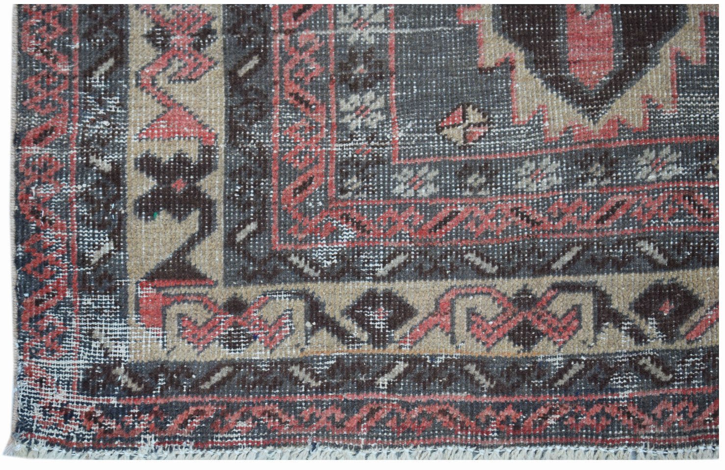 A vintage handwoven Persian rug featuring a geometric pattern in shades of red, black, and beige.