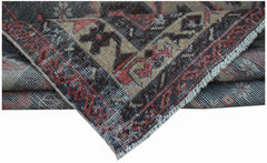 A handwoven vintage Persian rug featuring a worn, intricate pattern in red, brown, and tan tones.