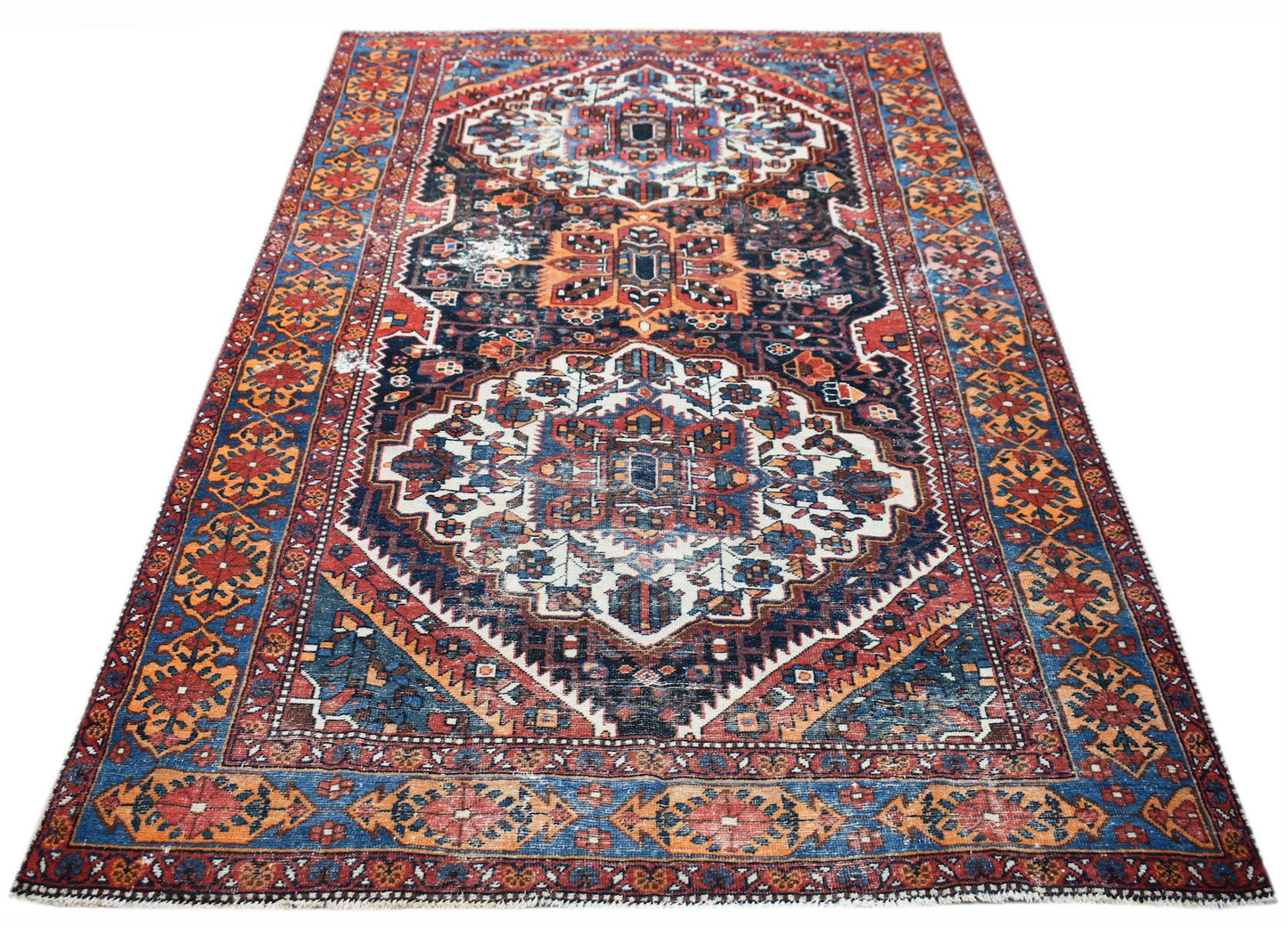 A handwoven vintage Persian rug featuring a traditional geometric pattern in red, blue, and cream.