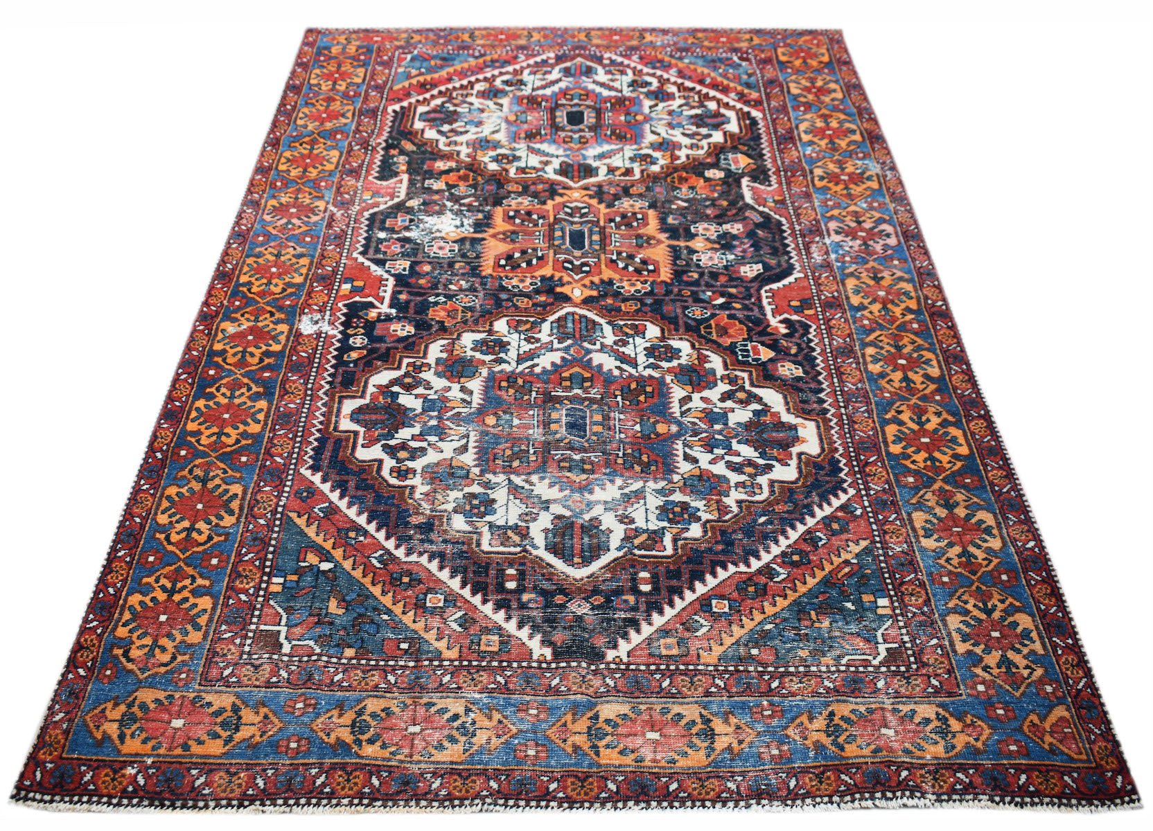 A handwoven vintage Persian rug featuring a traditional geometric pattern in red, blue, and cream.