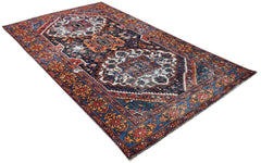 A handwoven vintage Persian rug featuring intricate geometric patterns in red, blue, and cream.