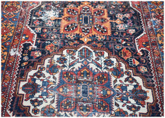 A vintage handwoven Persian rug featuring a traditional geometric pattern in blue, red, and orange.