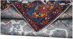 A folded vintage Persian rug featuring intricate floral patterns in blue, red, and orange tones.