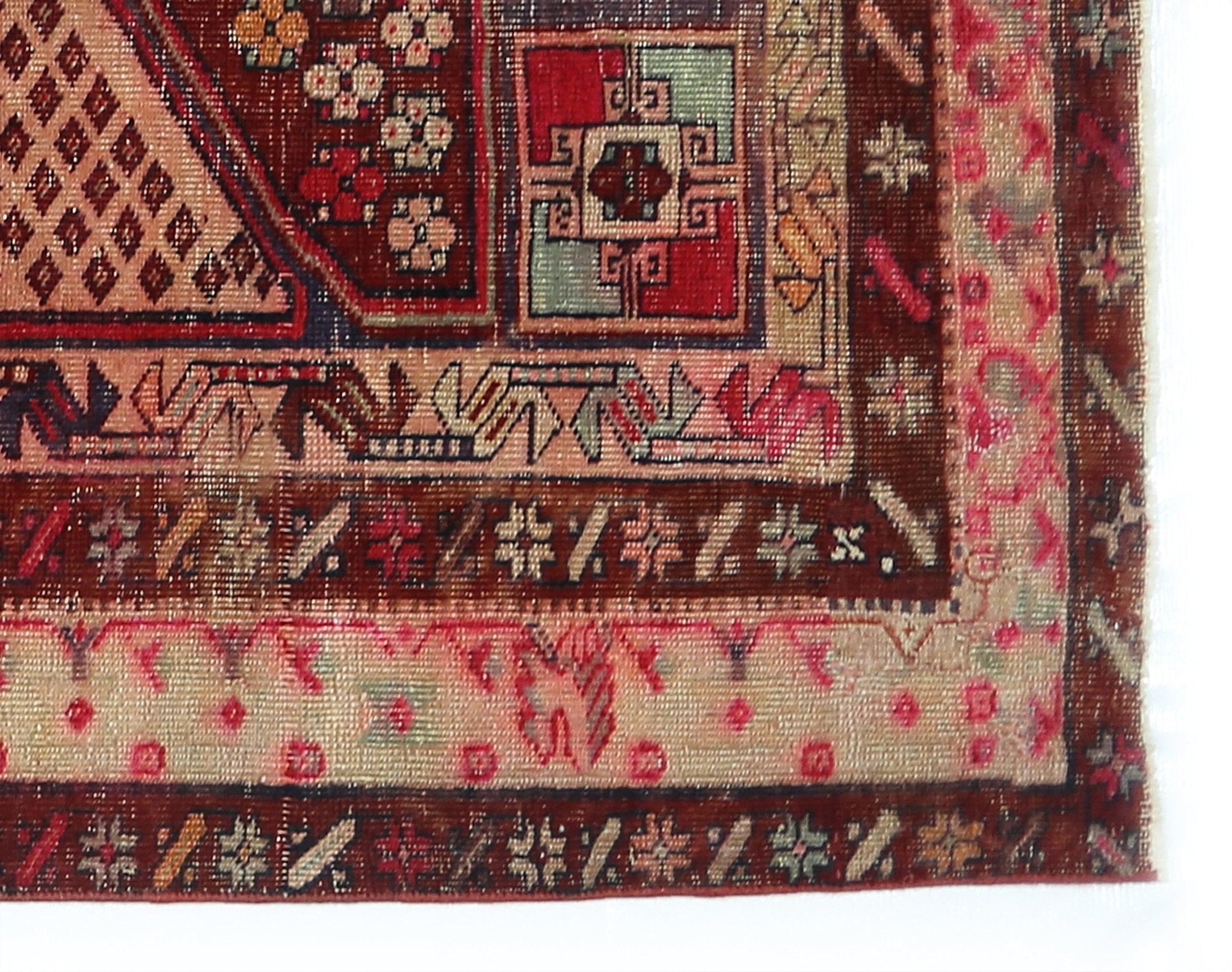 A vintage Persian rug featuring intricate geometric patterns in red, cream, and blue tones.