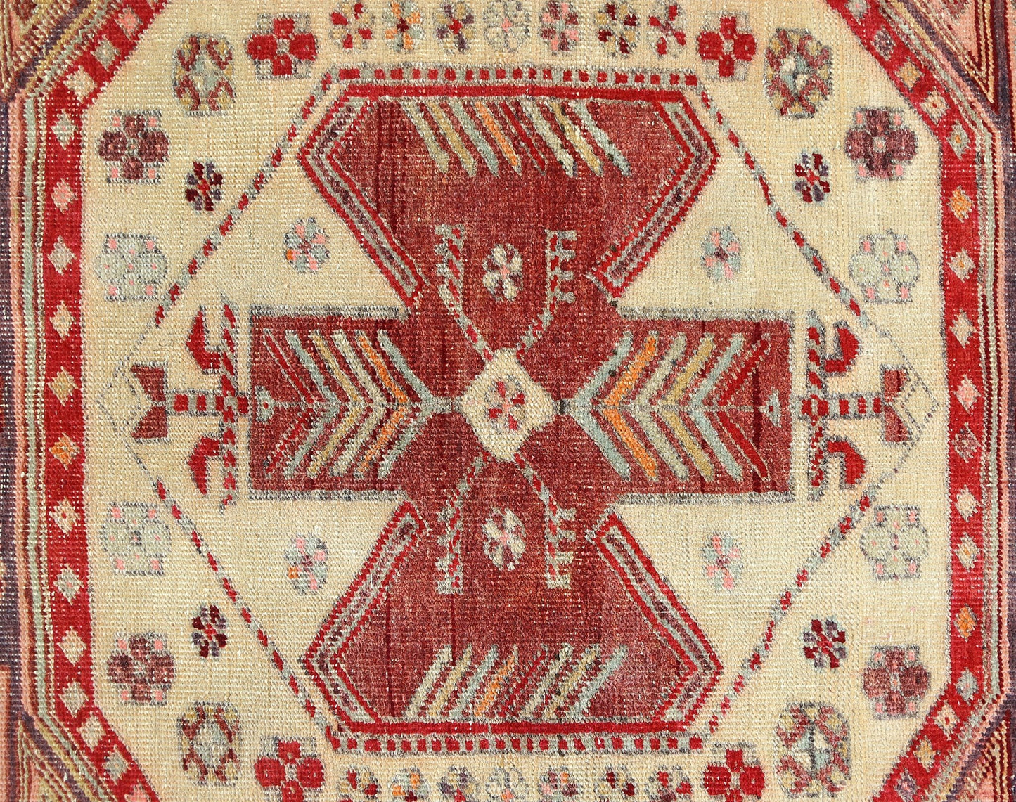 A vintage Persian rug featuring a central geometric medallion in red and cream tones.