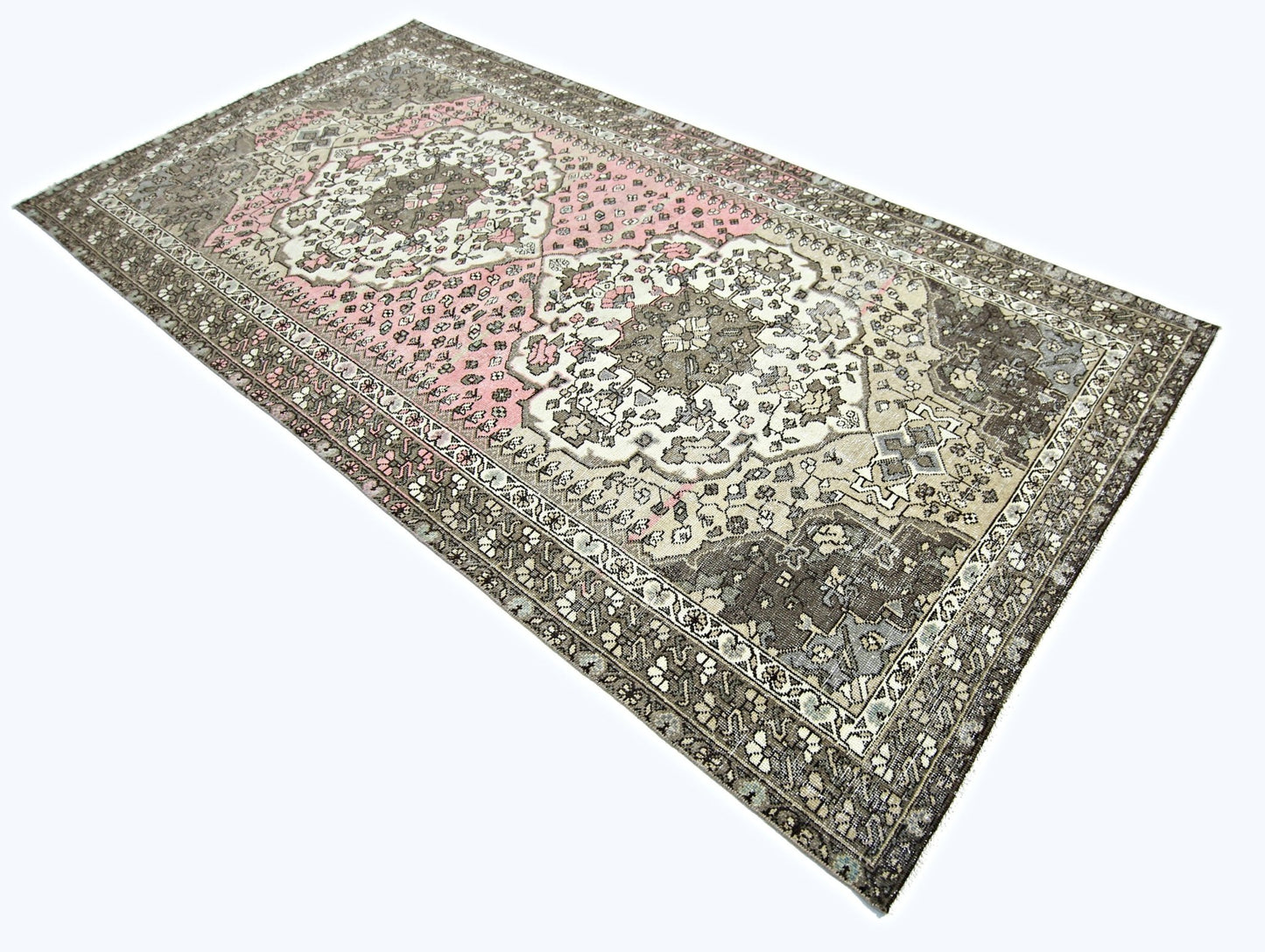 A rectangular vintage Persian rug featuring a floral pattern in shades of pink, grey, and cream.