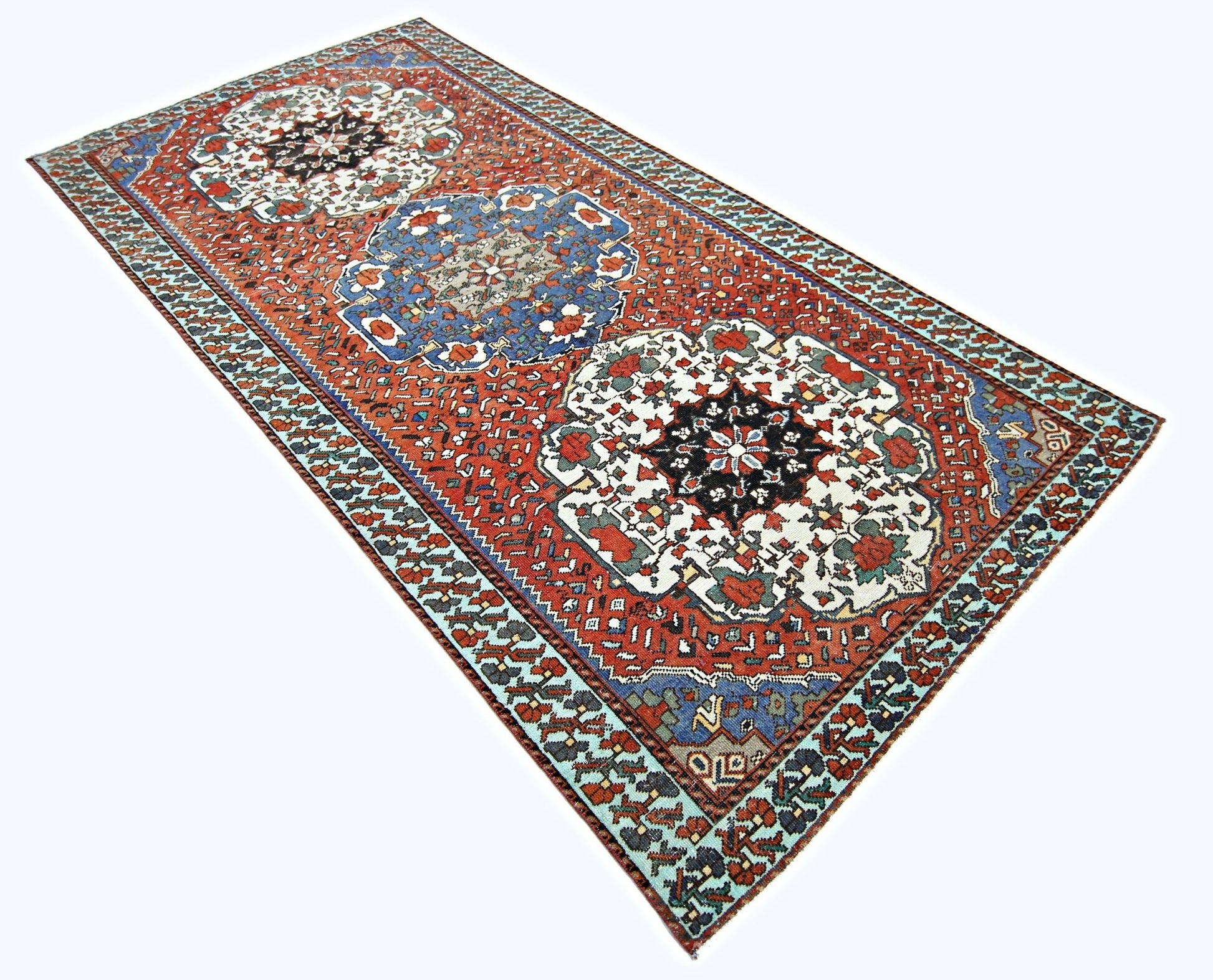A vintage handmade Persian rug featuring three large floral medallions on a red field.