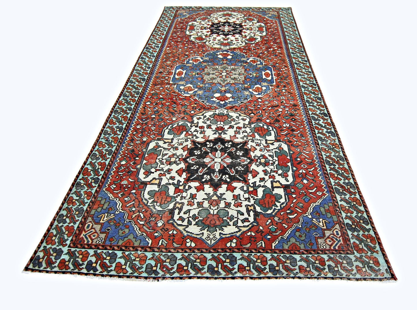 A vintage handmade Persian runner rug featuring a geometric floral pattern in red, blue, and white.