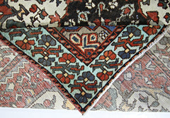 A vintage handmade Persian rug featuring a geometric floral pattern in vibrant colors.