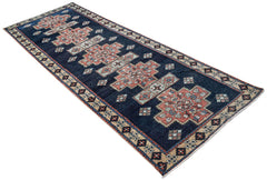 A vintage Persian Ardabil runner featuring geometric floral medallions on a dark blue field.