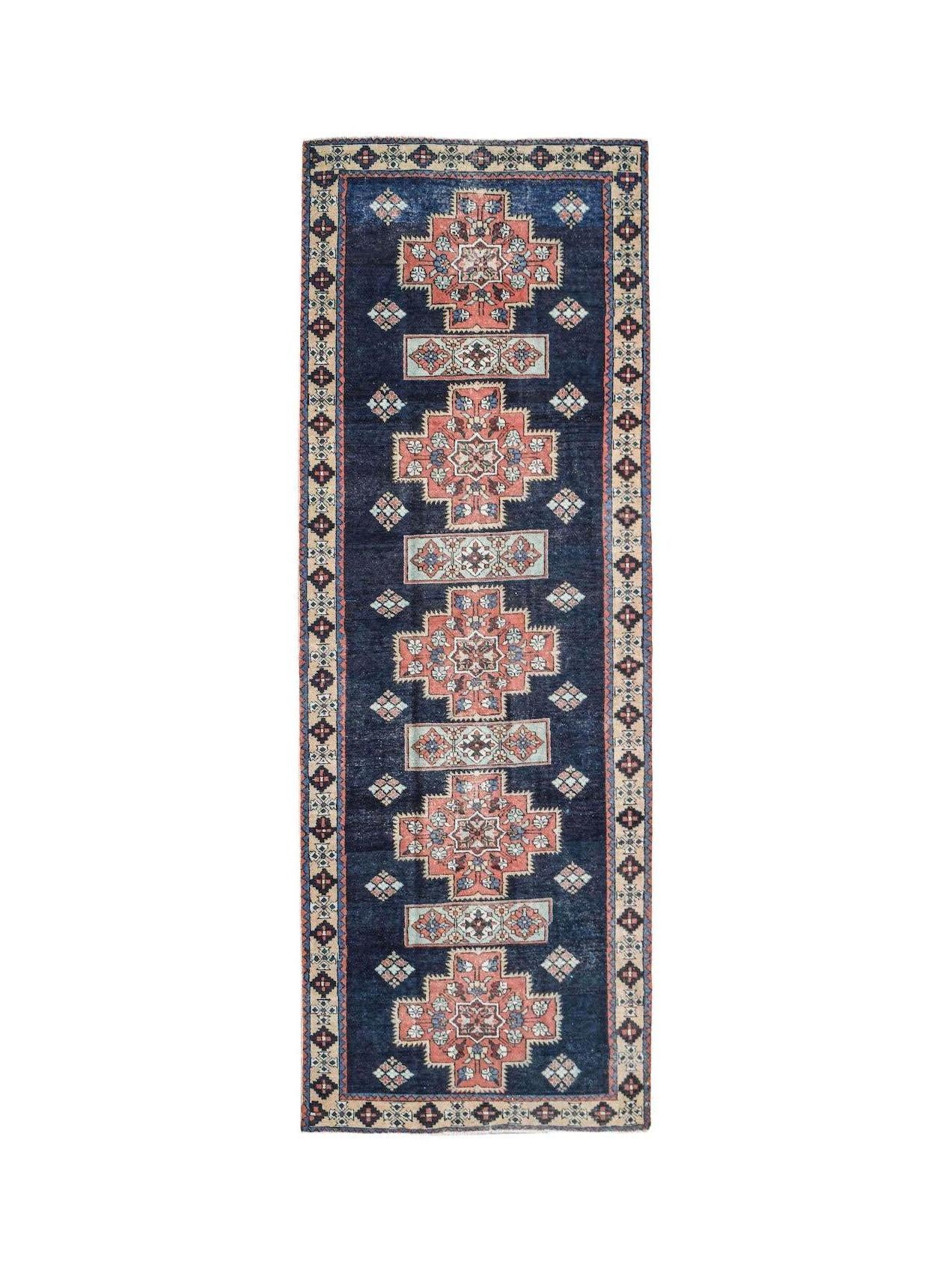 A vintage Persian Ardabil runner featuring geometric medallions on a deep blue wool field.