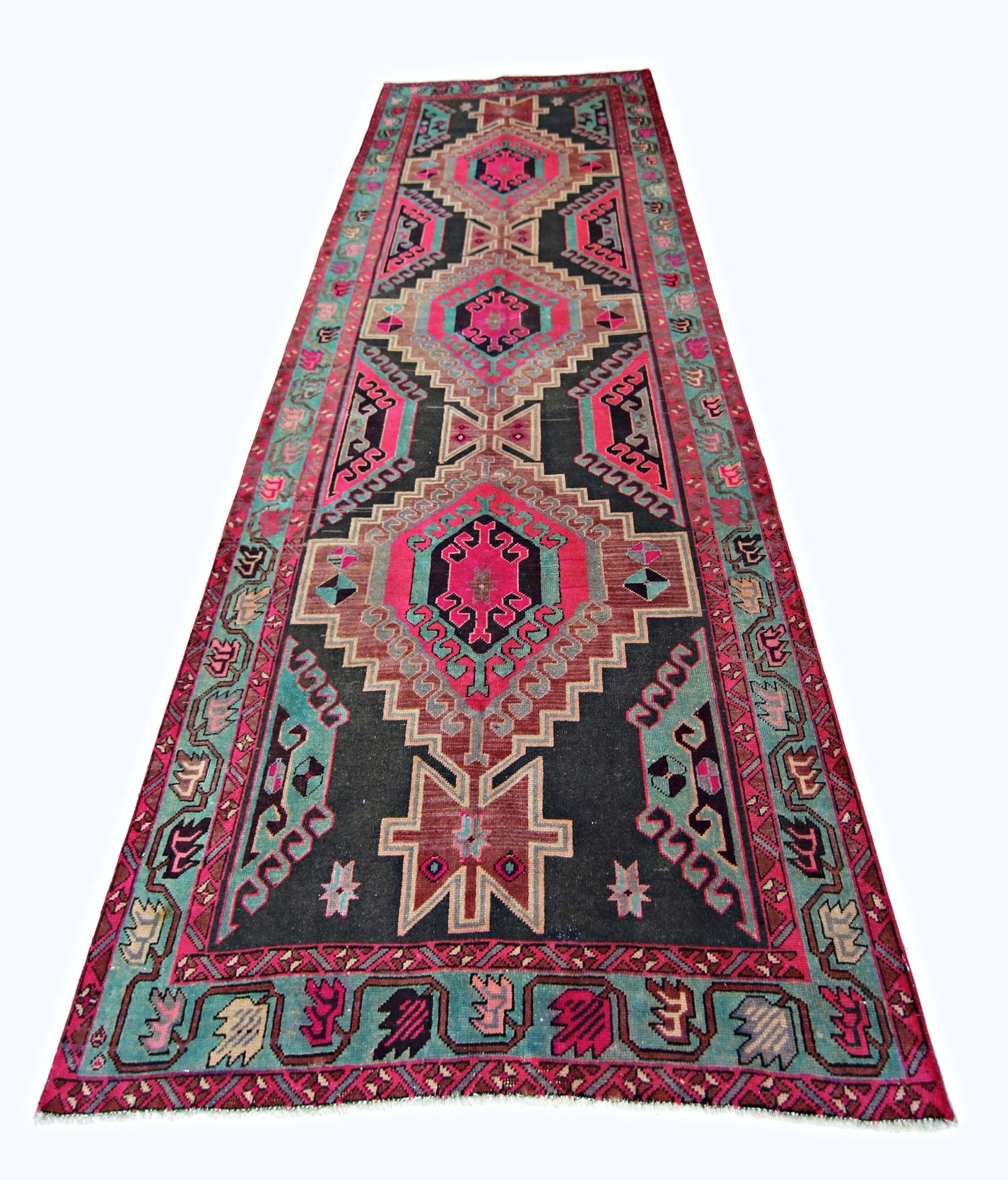 A vintage Persian Ardabil runner featuring geometric medallions in vibrant pink and teal on black.