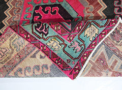 A vintage Persian Ardabil runner featuring a geometric pattern in vibrant pink and teal wool.