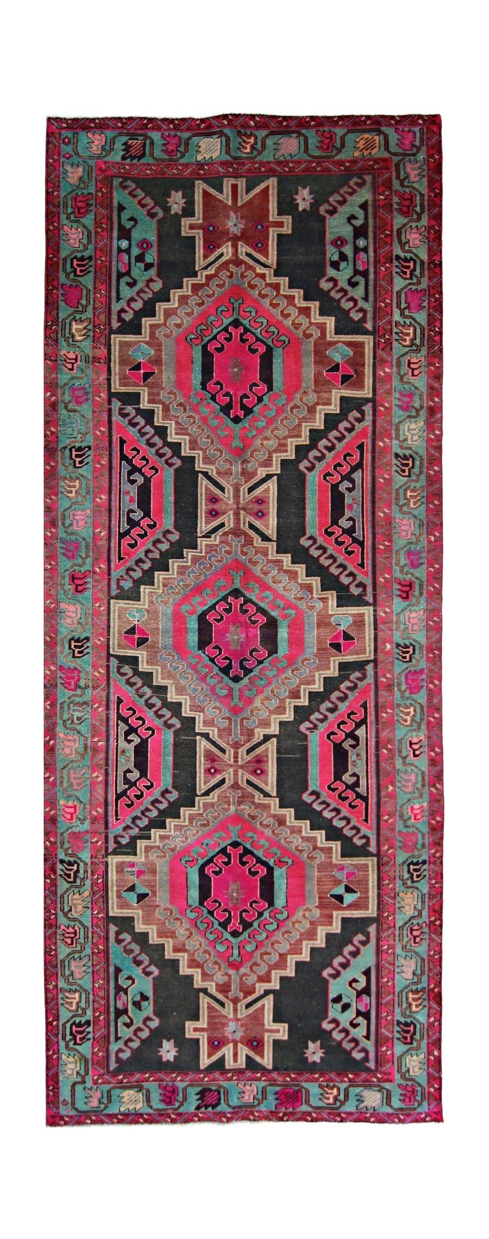 A vintage Persian Ardabil runner featuring a geometric pattern in vibrant pink, teal, and black.
