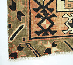 A close-up of a vintage Persian Ardabil runner featuring geometric patterns in olive and peach.