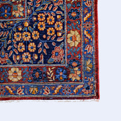 A vintage Persian Moud rug featuring a floral pattern in blue, red, and gold tones.