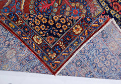 A vintage Persian Moud rug with intricate floral patterns in blue and red, shown folded.