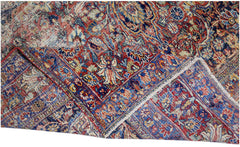 A vintage Persian Moud rug featuring intricate floral patterns in red, blue, and cream tones.