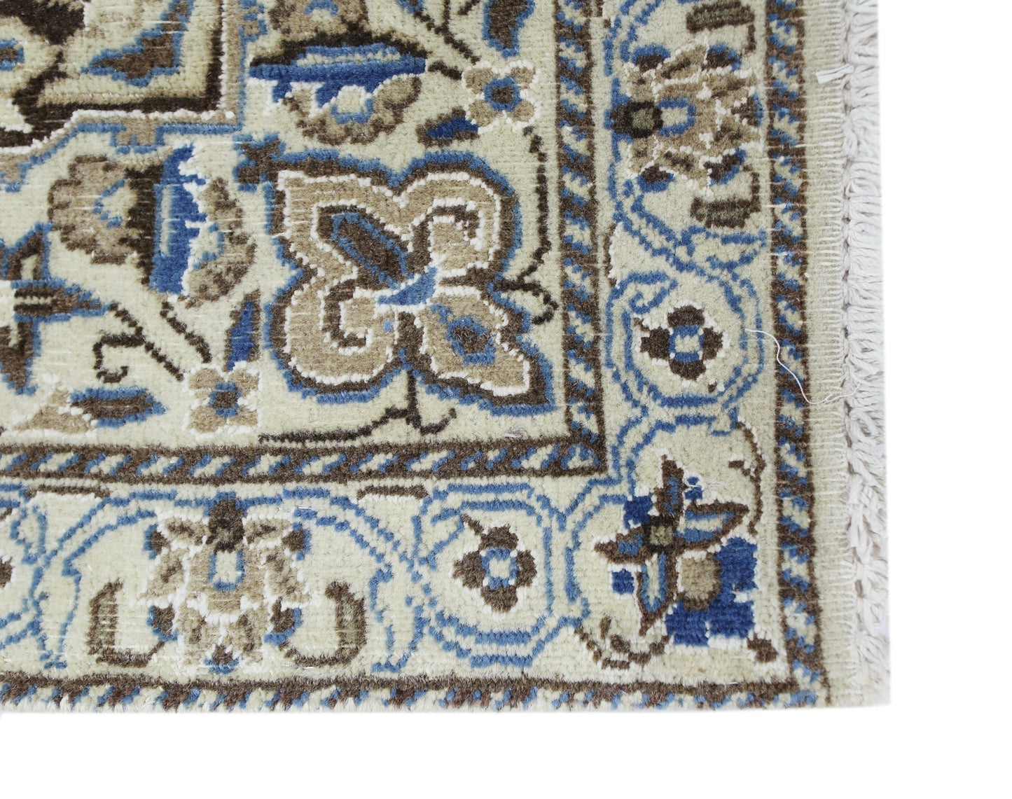 A corner detail of a vintage Persian Nain rug featuring intricate blue and beige floral patterns.