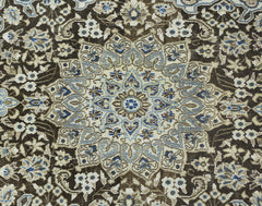 A vintage Persian Nain rug featuring an intricate floral medallion pattern in blue, beige, and brown.