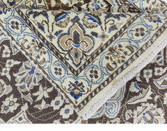 A vintage Persian Nain rug featuring intricate floral patterns in shades of blue, brown, and cream.