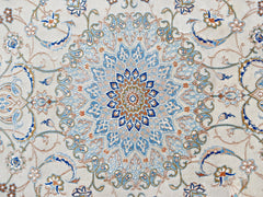 A vintage Persian Nain rug featuring an intricate blue and beige floral medallion pattern.