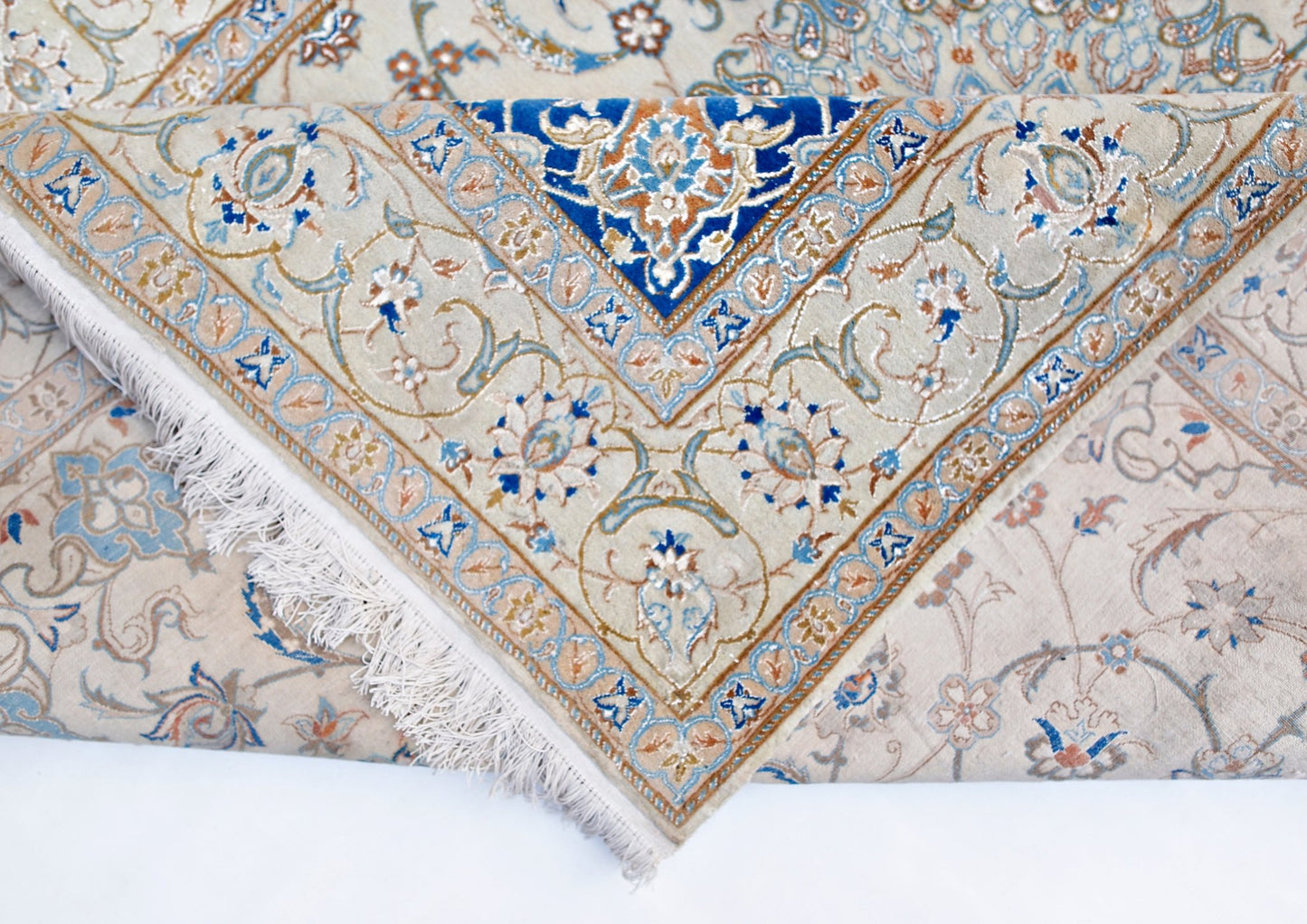A vintage Persian Nain rug featuring intricate floral patterns in blue and cream on a wool pile.