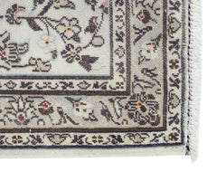 A vintage Persian Nain runner featuring intricate floral patterns in blue and brown on a cream base.