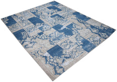 A rectangular vintage patchwork rug featuring a blue and cream floral pattern.