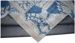 A vintage patchwork rug featuring blue and beige floral patterns with a grey fabric backing.