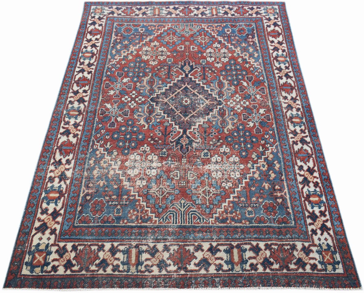 A vintage handwoven Persian Ghashghai rug featuring a geometric medallion pattern in red and blue.