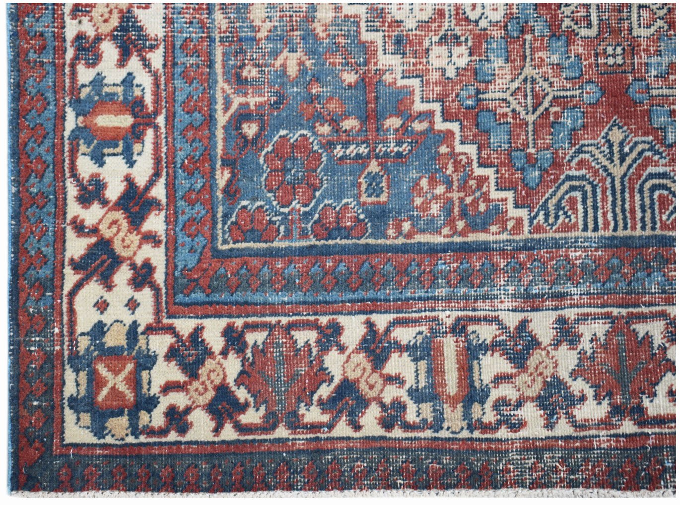 A vintage Persian Ghashghai rug featuring a geometric floral pattern in red, blue, and cream.