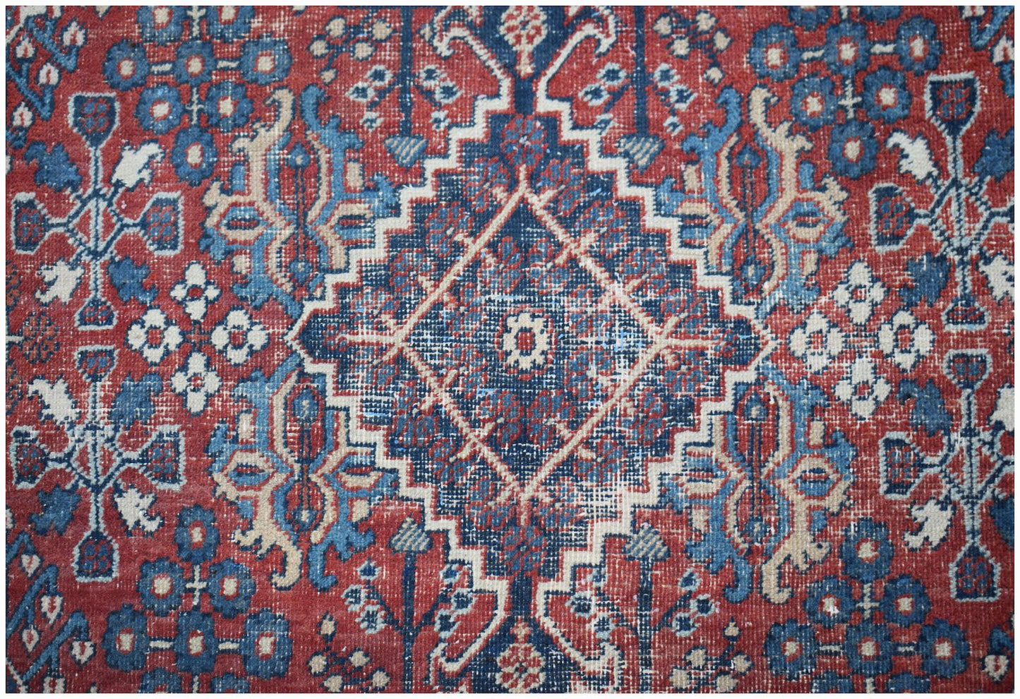 A vintage Persian Ghashghai rug featuring a geometric diamond pattern in red, blue, and cream.