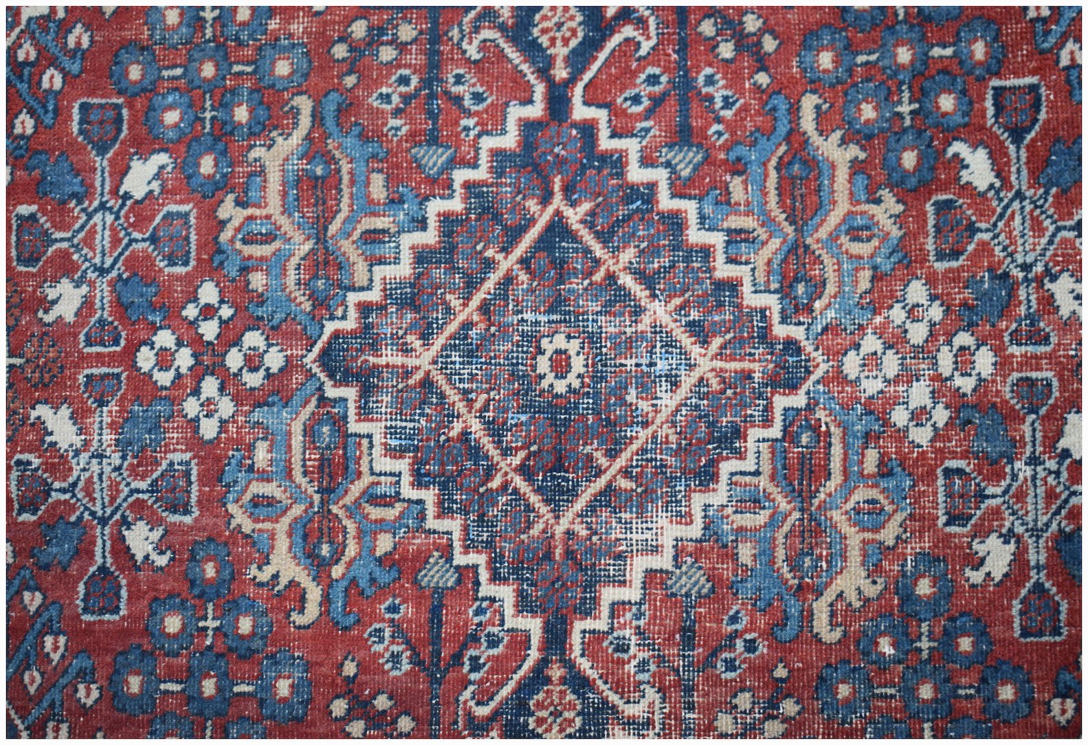 A vintage Persian Ghashghai rug featuring a geometric diamond pattern in red, blue, and cream.
