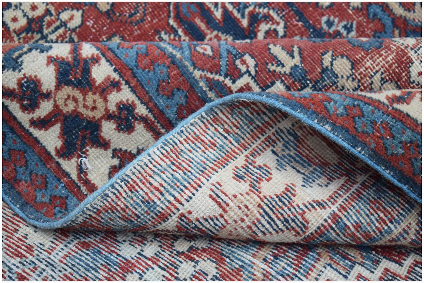 A handwoven vintage Persian Ghashghai rug featuring a traditional red and blue geometric pattern.