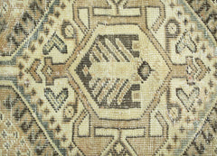 A close-up of a vintage Persian Qashqai rug featuring intricate geometric patterns in neutral tones.