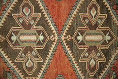A vintage Persian rug featuring geometric diamond patterns in shades of brown, orange, and blue.