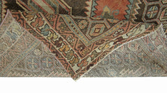A folded vintage Persian rug featuring intricate geometric patterns in warm, earthy tones.