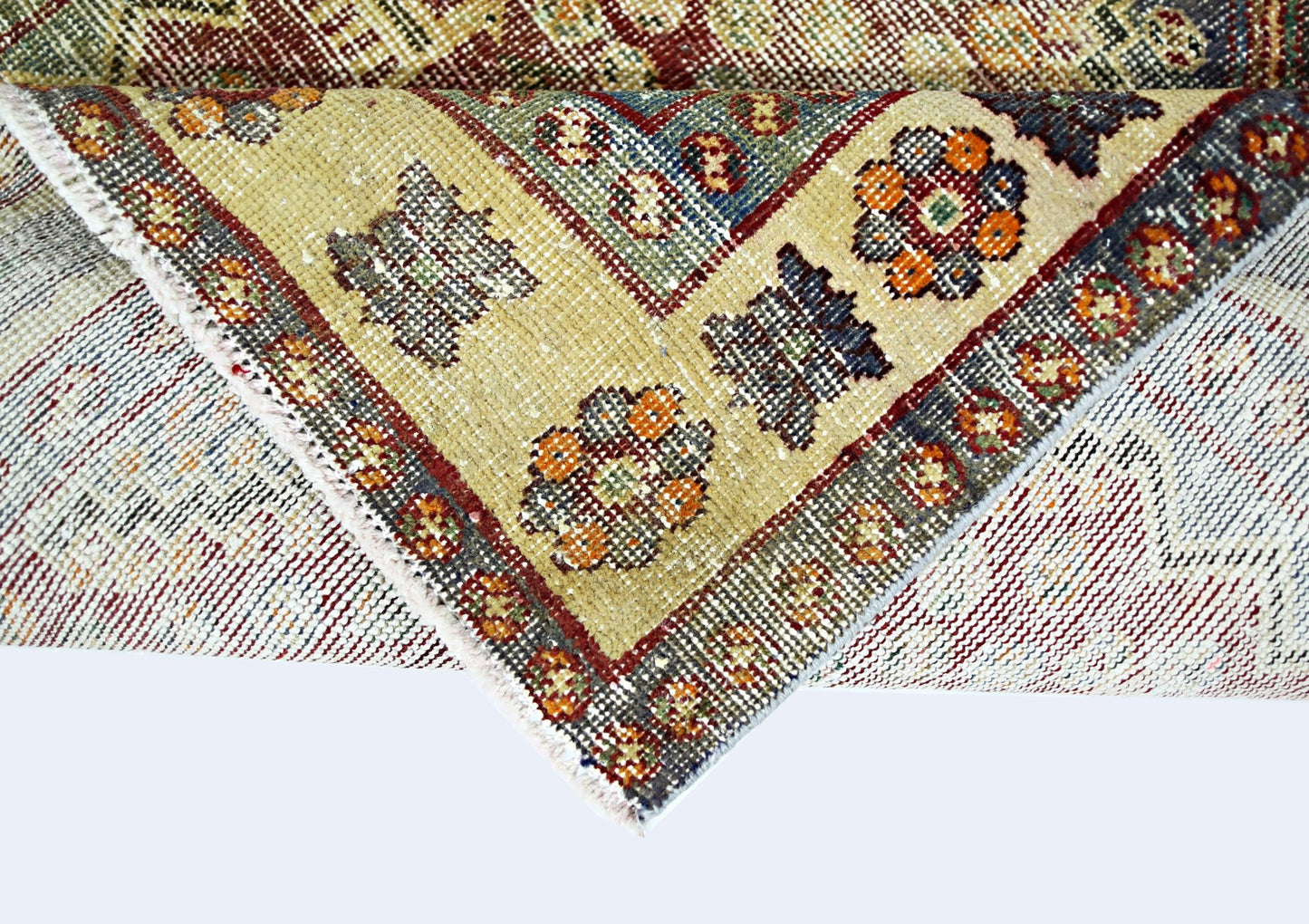 A folded vintage Persian Qashqai rug featuring intricate geometric patterns in wool on a cotton base.