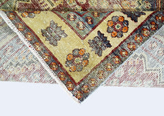 A folded vintage Persian Qashqai rug featuring intricate geometric patterns in wool on a cotton base.