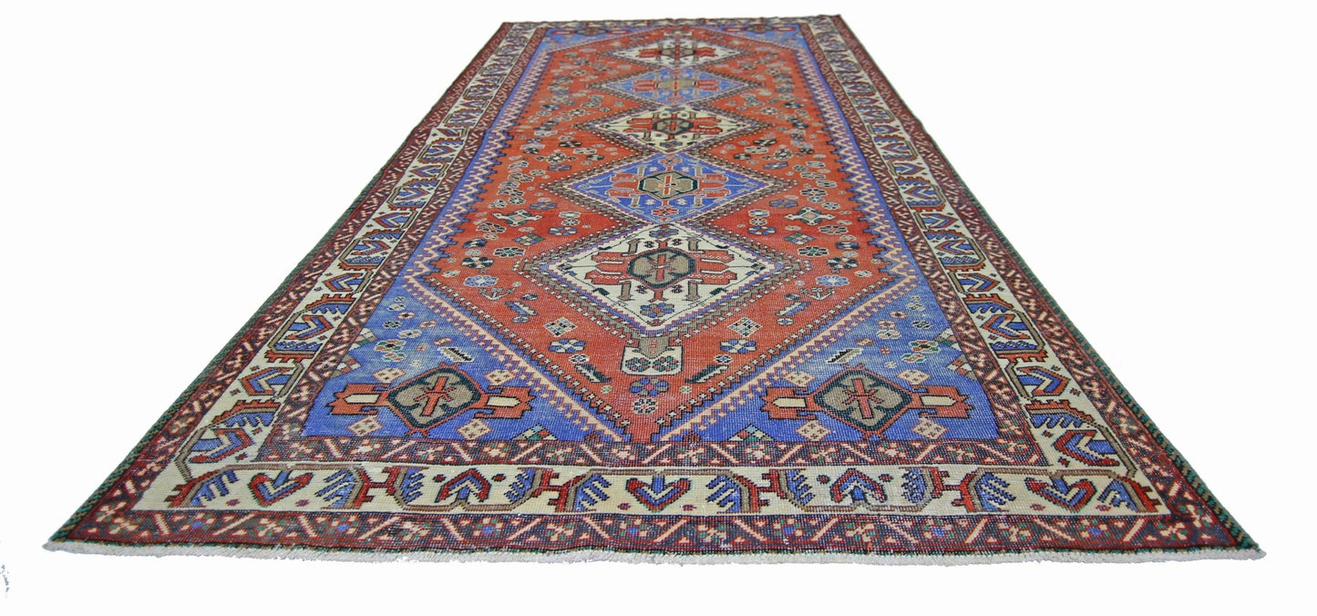 A vintage Persian Ghashghai rug featuring a geometric diamond pattern in red and blue tones.