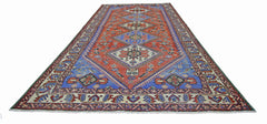 A vintage Persian Ghashghai rug featuring a geometric diamond pattern in red and blue tones.