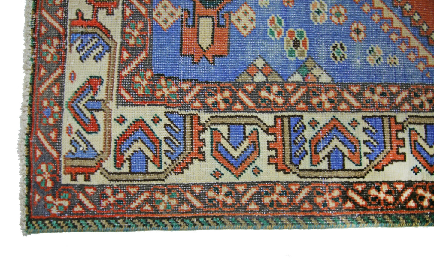 A close-up of a vintage Persian Ghashghai rug featuring intricate geometric patterns in blue and red.