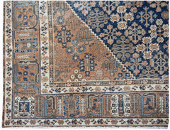 A vintage Persian Ghashghai rug featuring intricate geometric patterns in blue and terracotta tones.