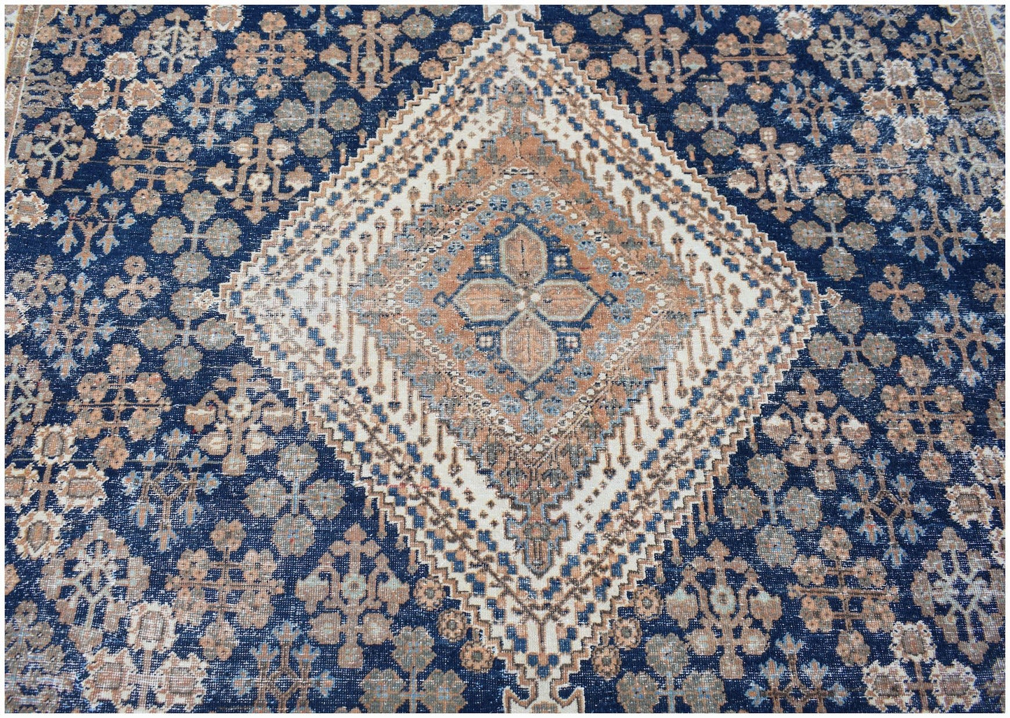 A vintage Persian Ghashghai rug featuring a central diamond medallion on a deep blue field.