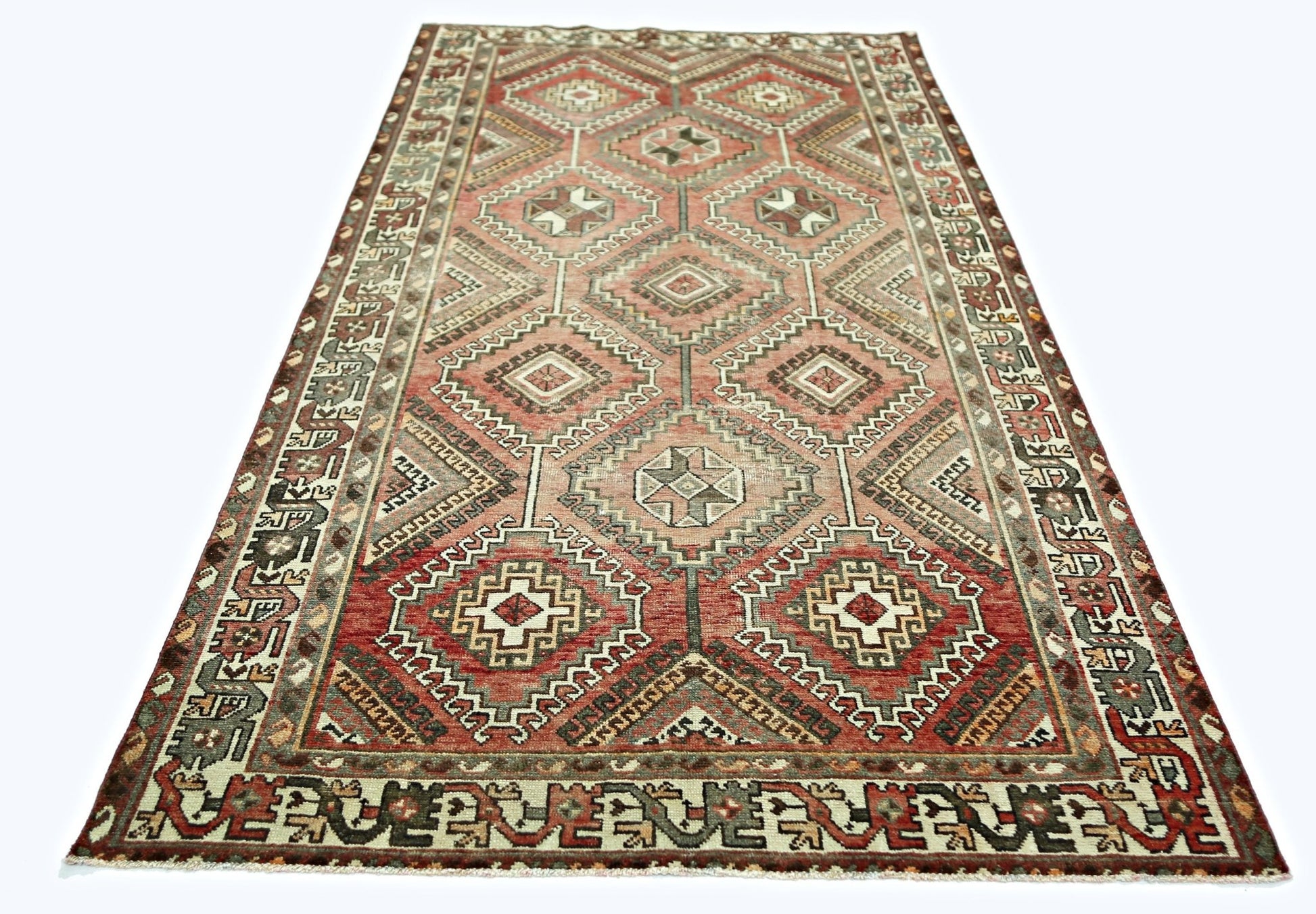 A handmade vintage Persian rug featuring a geometric diamond pattern in shades of red and brown.