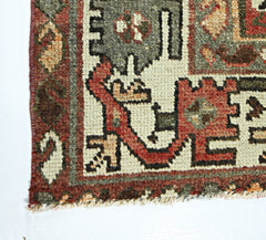 A close-up of a vintage Persian rug featuring intricate geometric patterns in red, green, and cream.