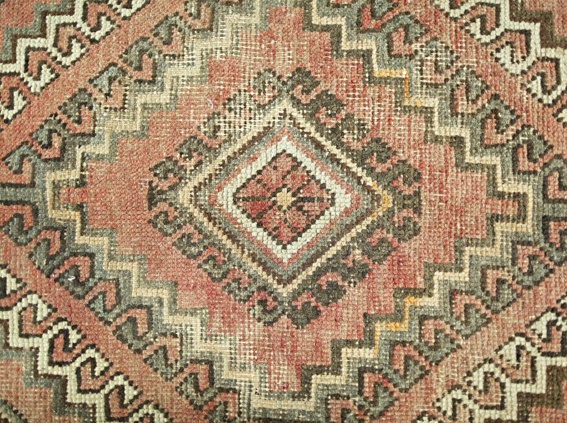 A vintage Persian rug featuring a geometric diamond pattern in shades of red, grey, and cream.